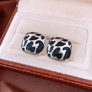 Chic silver square stud earrings with black leopard pattern inlay in a beige jewelry box