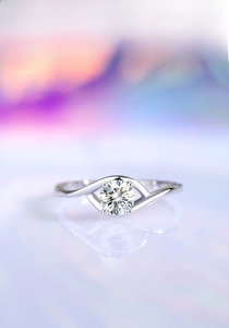 Macro shot of 0.5ct moissanite ring with twisted band and four-prong setting on a reflective base