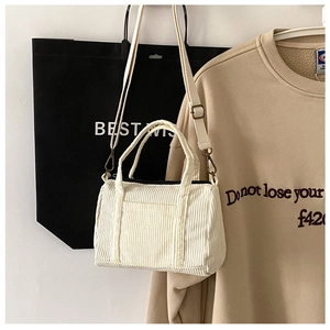 Detail of the cream corduroy Boston bag with adjustable strap against a casual backdrop