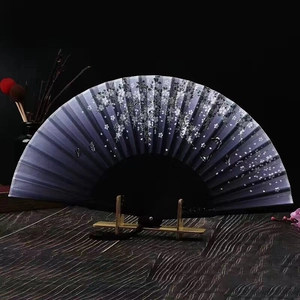 Detailed close-up of a folding fan with cherry blossoms on a wooden display stand