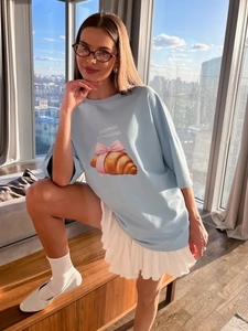 Λεπτομέρεια από γαλάζιο βαμβακερό T-shirt με τύπωμα κρουασάν, ροζ φιόγκο και ρωσικό κείμενο