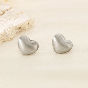 Boucles d'oreilles cœur argent mat avec texture brossée sur fond en pierre naturelle