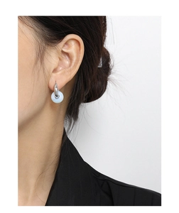 Detalle de un pendiente de aro plateado con cuenta azul claro en la oreja de la modelo