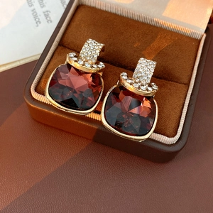 Macro shot of vintage gold earrings with large faceted burgundy square crystals