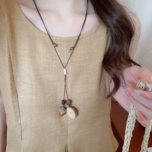 Dettaglio di una collana vintage in corda di cera con ciondoli a forma di ghianda e pomodoro in legno
