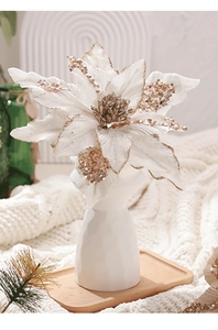 Détail de fleur de Noël en velours crème avec paillettes dorées dans un vase élégant