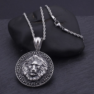 Detailed view of silver lion head pendant necklace on black stone with twisted rope chain