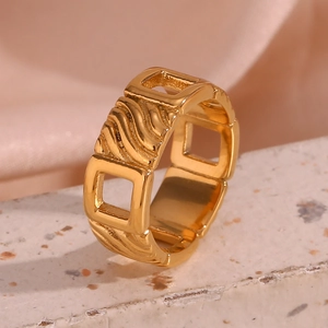 Macro detail of 18K gold-plated square ring with hollow design on terrazzo and silk