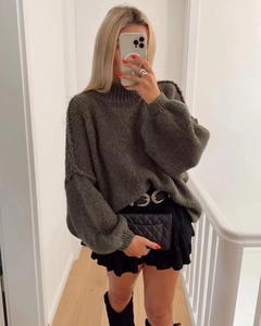Detailed texture of thick olive green knit sweater paired with a black tiered mini skirt