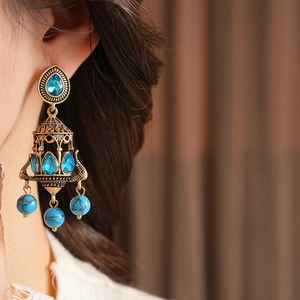 Detailed close-up of vintage bronze chandelier earrings with blue stones on a model