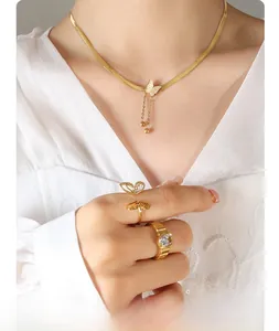 Close-up of golden butterfly necklace and rings set worn by model in soft lighting