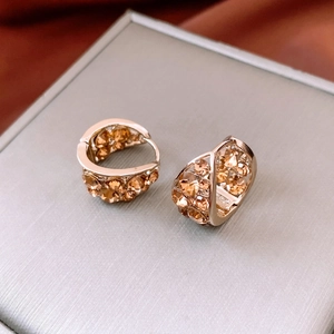 Dettaglio di orecchini vintage a U con cristalli champagne su una scatola di metallo