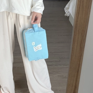 Close-up of model holding the light blue dog print makeup bag with a sturdy side handle