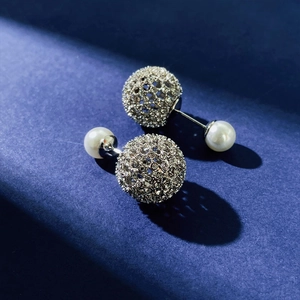 Macro detail of silver double-sided stud earrings with rhinestones and white pearls
