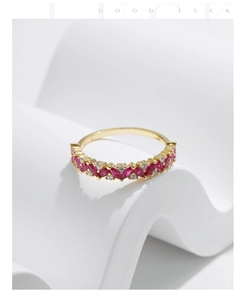 Detailed close-up of a gold ring with Marquise red gems and white diamonds on white stone