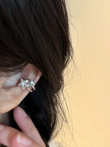 Detail of silver star ear cuff with sparkling zircon inlay worn on a model's ear