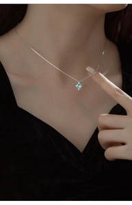 Macro shot of a silver star pendant featuring a light blue topaz stone on neck