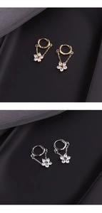 Detailed close-up of zircon flower drop earrings in gold and silver finish on matte tray