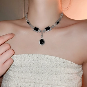 Close-up of a silver necklace with black teardrop pendant on a model's collarbone