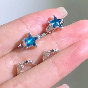 Detailed view of silver star rings with blue zircon stone and crystal pave on fingers