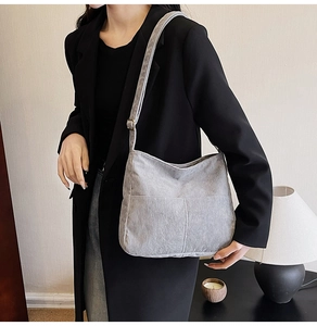 Detail view of gray corduroy messenger bag with adjustable strap worn on shoulder