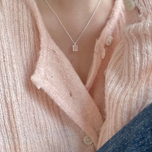 Close-up of minimalist silver geometric square pendant on a delicate chain necklace