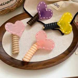 Quatre élastiques à cheveux en spirale avec cœurs colorés sur un plateau en bois épuré
