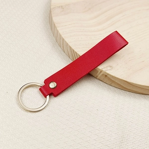Minimalist red leather keychain with polished gold metal ring and rivet for bags