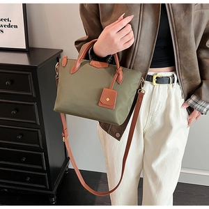 Detailed view of green nylon tote bag with brown leather handles worn as a crossbody bag