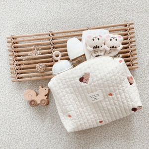 Detail of cream quilted cotton mommy bag featuring squirrel embroidery and soft texture