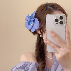 Detail of purple fabric orchid hair clip with pearl center on elegant woman