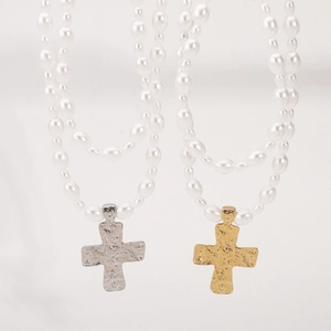 Detail of baroque pearl necklaces with hammered gold and silver cross pendants on white background