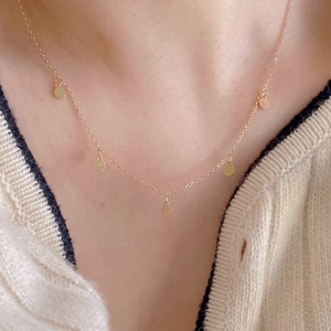 Close-up of minimalist gold sterling silver necklace with five shiny round disc pendants