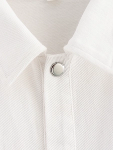 Macro shot of white twill fabric texture and silver metal button on a stylish jacket