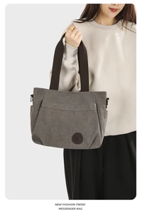 Grey canvas tote bag detail with brown strap worn by model, casual messenger style