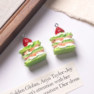Macro detail of two green napoleon cake pendants with cream and strawberry topping