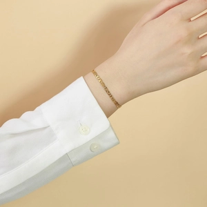 Detailed view of a gold-plated pig nose link bracelet on a woman wrist with a white cuff