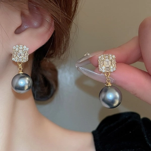 Détail des boucles d'oreilles papillon dorées avec zircon carré et perles grises