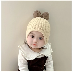 Detail of cream white knit baby hat featuring cute brown bear ears and ribbed texture