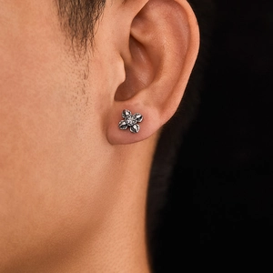 Detailed macro view of vintage titanium steel flower stud earring with aged silver finish