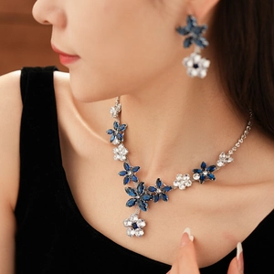 Close-up of elegant flower pendant necklace and earrings set with blue zircon stones