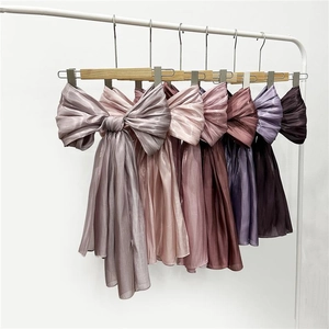 Detail of hanging large chiffon bow scarves in gradient shades of purple and pink