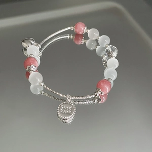 Makroaufnahme eines zweilagigen Perlenarmbands mit Opalsteinen und Herzanhänger aus Silber