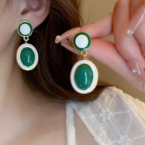 Detailed close-up of vintage heart earrings with green enamel and gold plated accents