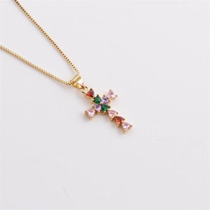 Detail of gold cross pendant with colorful heart-shaped zircons on a fine chain