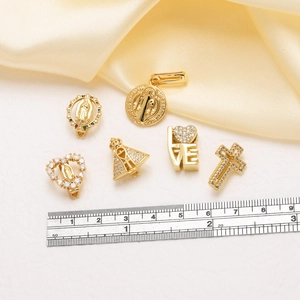 Detailaufnahme von 18k vergoldeten religiösen Anhängern mit Zirkonia auf Seidenstoff