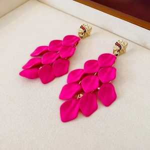 Macro detail of magenta acrylic flower petal fringe earrings with gold textured studs