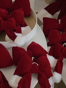 Close-up of red velvet Christmas bows with white faux fur trim in a festive pile