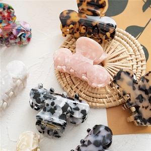 Assorted tortoise shell acetate hair claws and floral shark clips on a woven mat