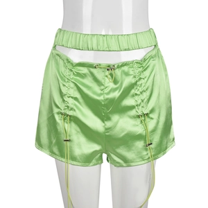 Detail of green satin shorts featuring hollow-out design and adjustable drawstring buckles